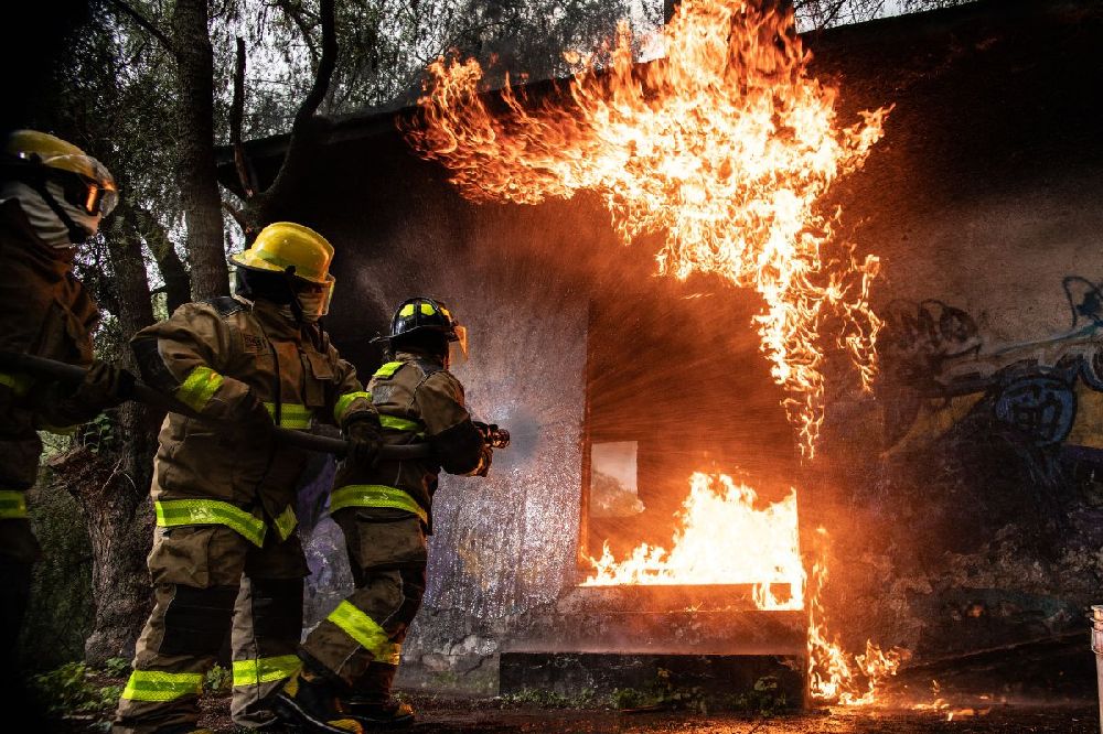 firefighters putting out a house fire caused by a bushfire
